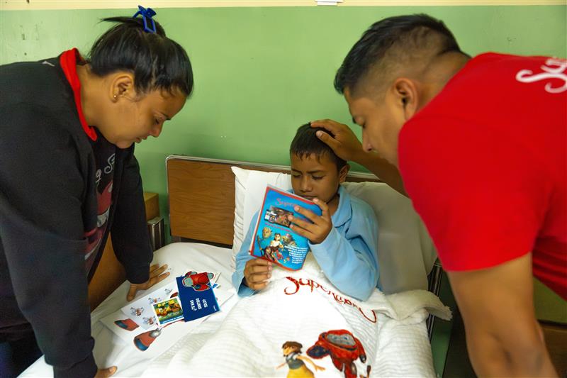 Osman, his mom, and a Superbook team member pray over Osman before his eye surgery.